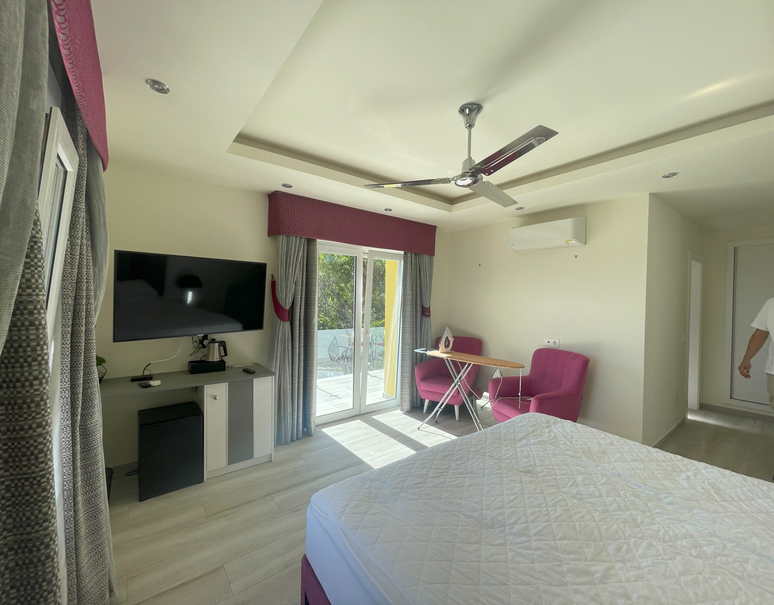 Suite existente con sillones rosas, televisión y puertas acristaladas hacia la terraza