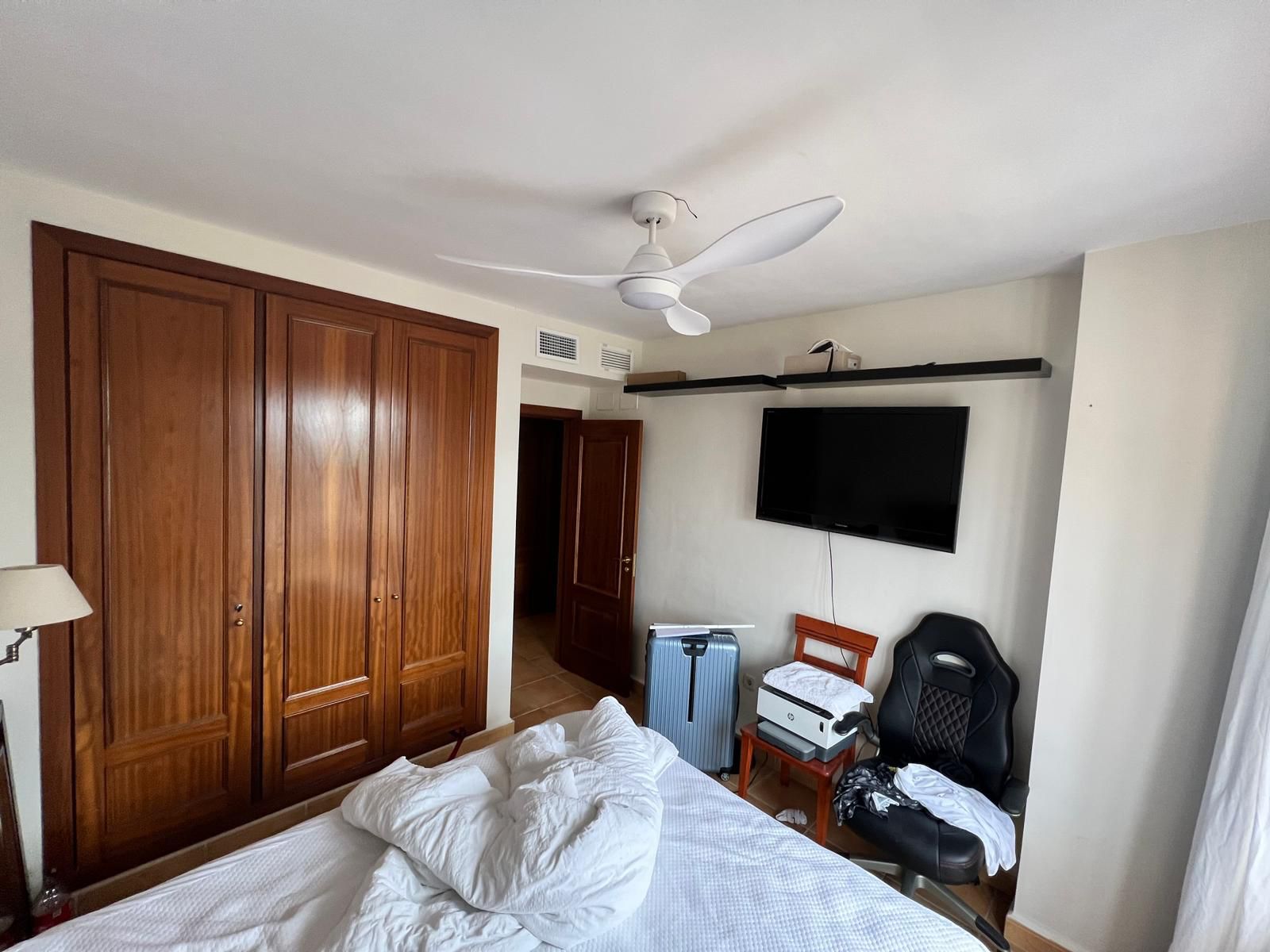 Dormitorio existente con armario de madera, televisión mural y ventilador de techo