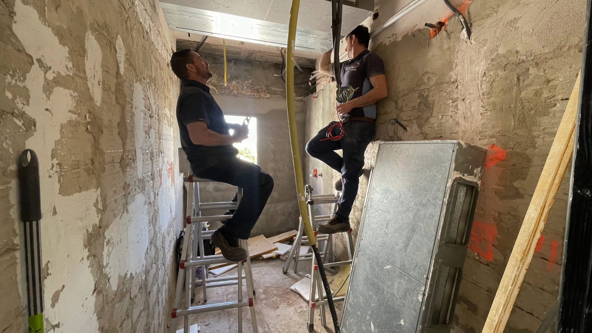 Baño durante la obra con paredes sin revestir y profesionales preparando instalaciones