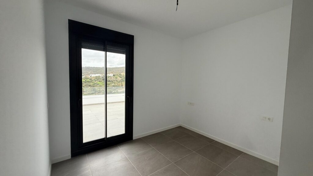 Dormitorio vacío con puertas de terraza antes del proyecto en Manilva